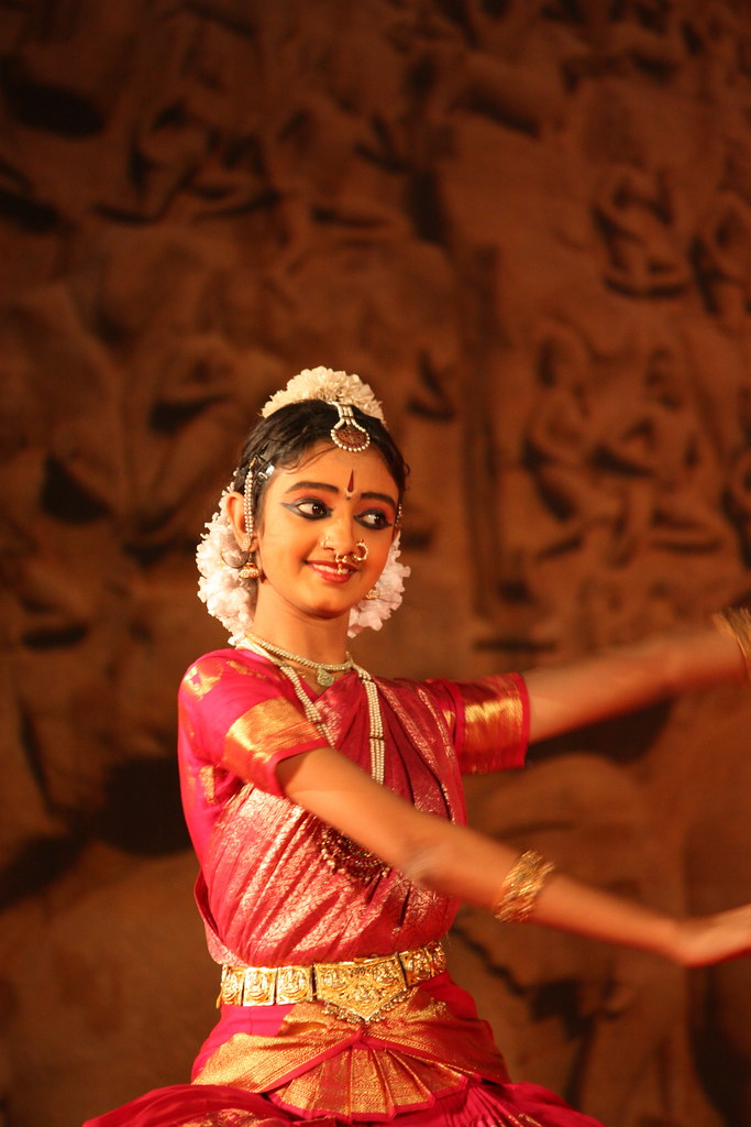 Indian classical dancer in a traditional red and green silk costume performing a Bharatanatyam pose